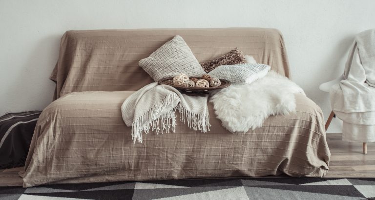 Modern interior of the living room with a sofa and decorative items . Decorative pillows and blankets. Coziness and comfort at home .