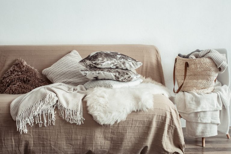 Modern interior of the living room with a sofa and decorative items . Decorative pillows and blankets. Coziness and comfort at home .