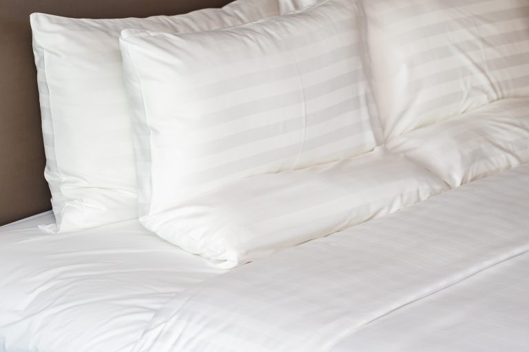 White comfortable Pillow on bed with blanket decoration interior of bedroom